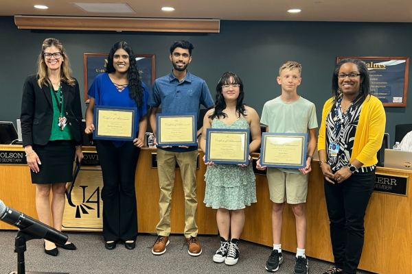  four students stand holding a certificate with the superintendent and board member